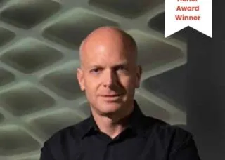 bald man black shirt arms crossed staring at camera