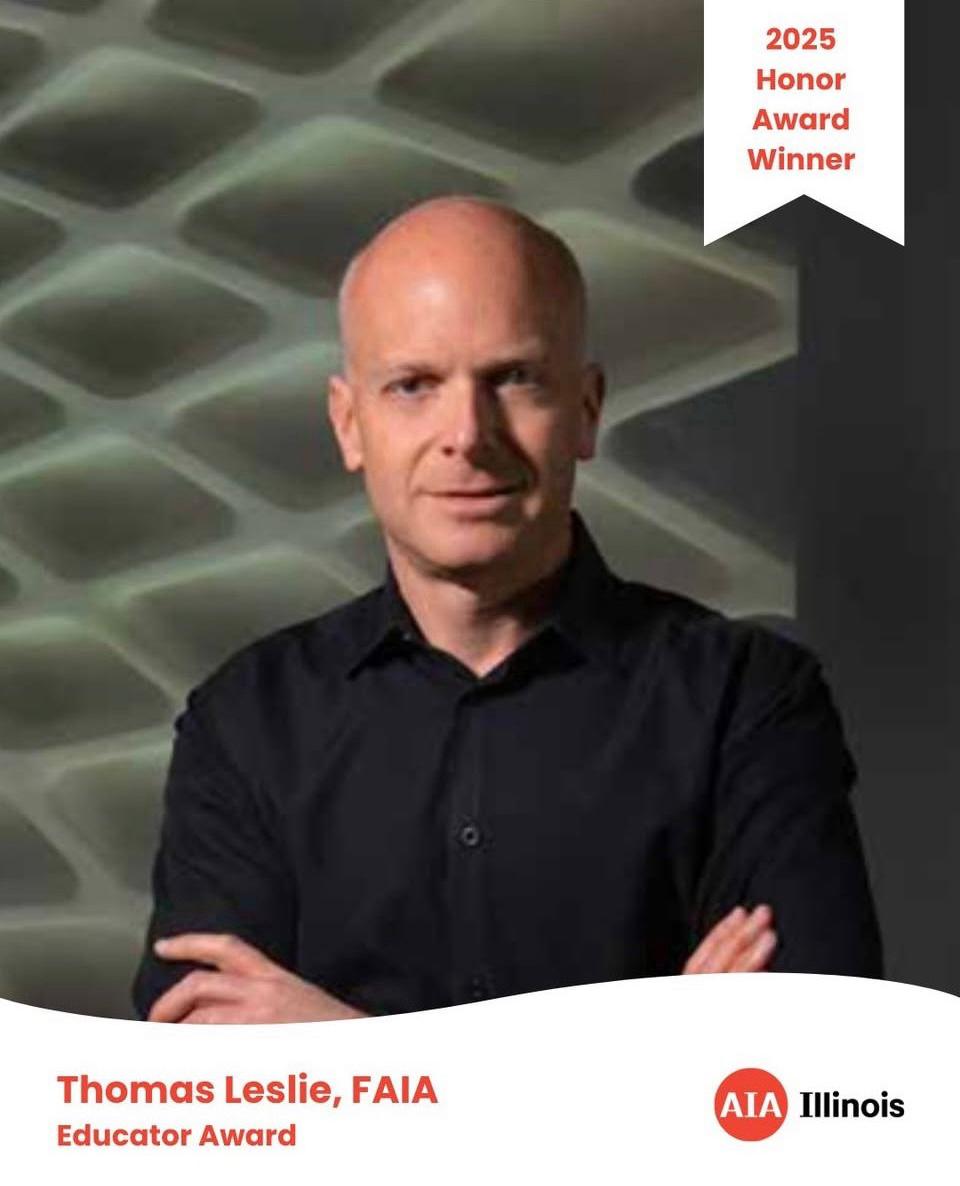 bald man black shirt arms crossed staring at camera