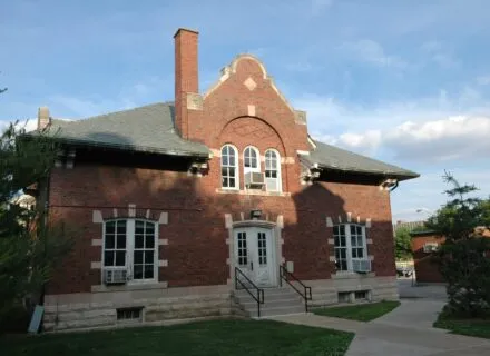 picture of the outside of architecture annex with 7 windows, a chimnew, stairs up to double doors that are white