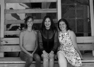 Three women sitting on a bench and smiling