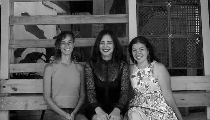 Three women sitting on a bench and smiling