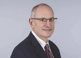 Caucasian male with grey and black hair in black suit