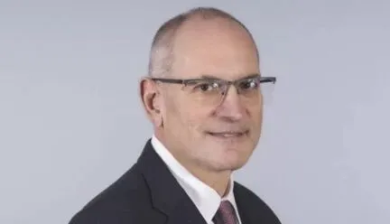Caucasian male with grey and black hair in black suit