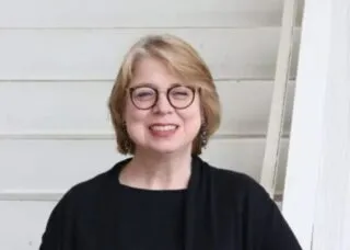 picture of blonde with black outfit and round glasses
