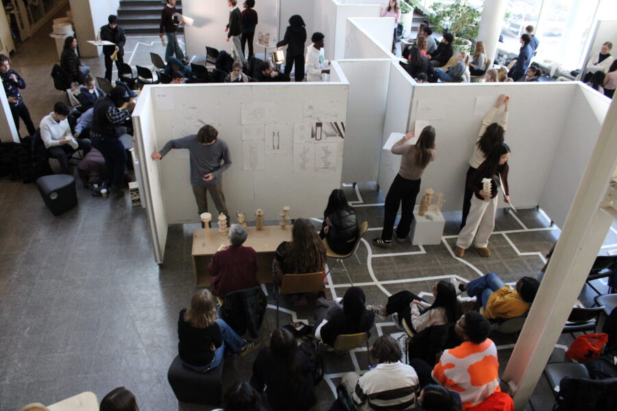 Students pinning up their work on white z panels in the atrium