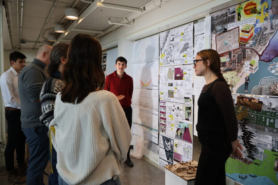 two students presenting their work pinned up on a wall