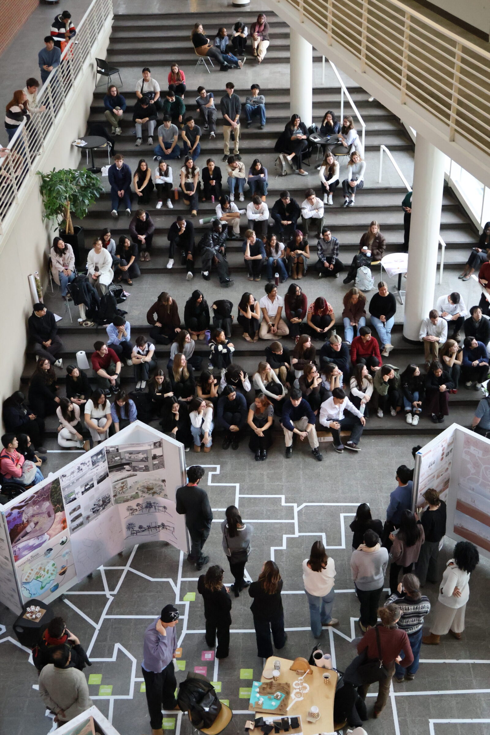overhead view of atrium with many students sitting on stair steps, reviewers and z panels