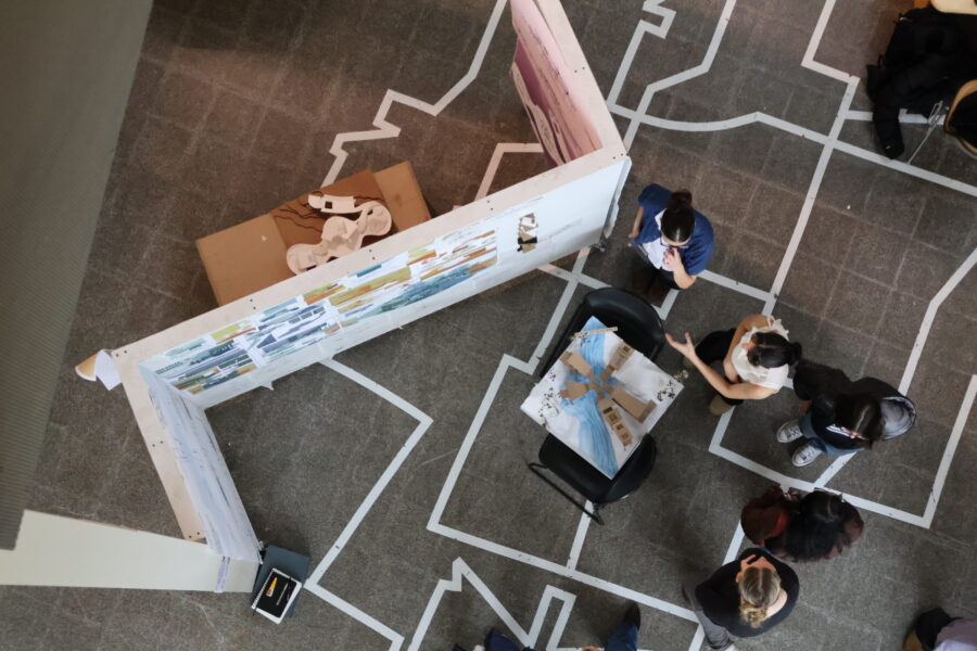 overhead view of students presenting projects pinned up on white z panels