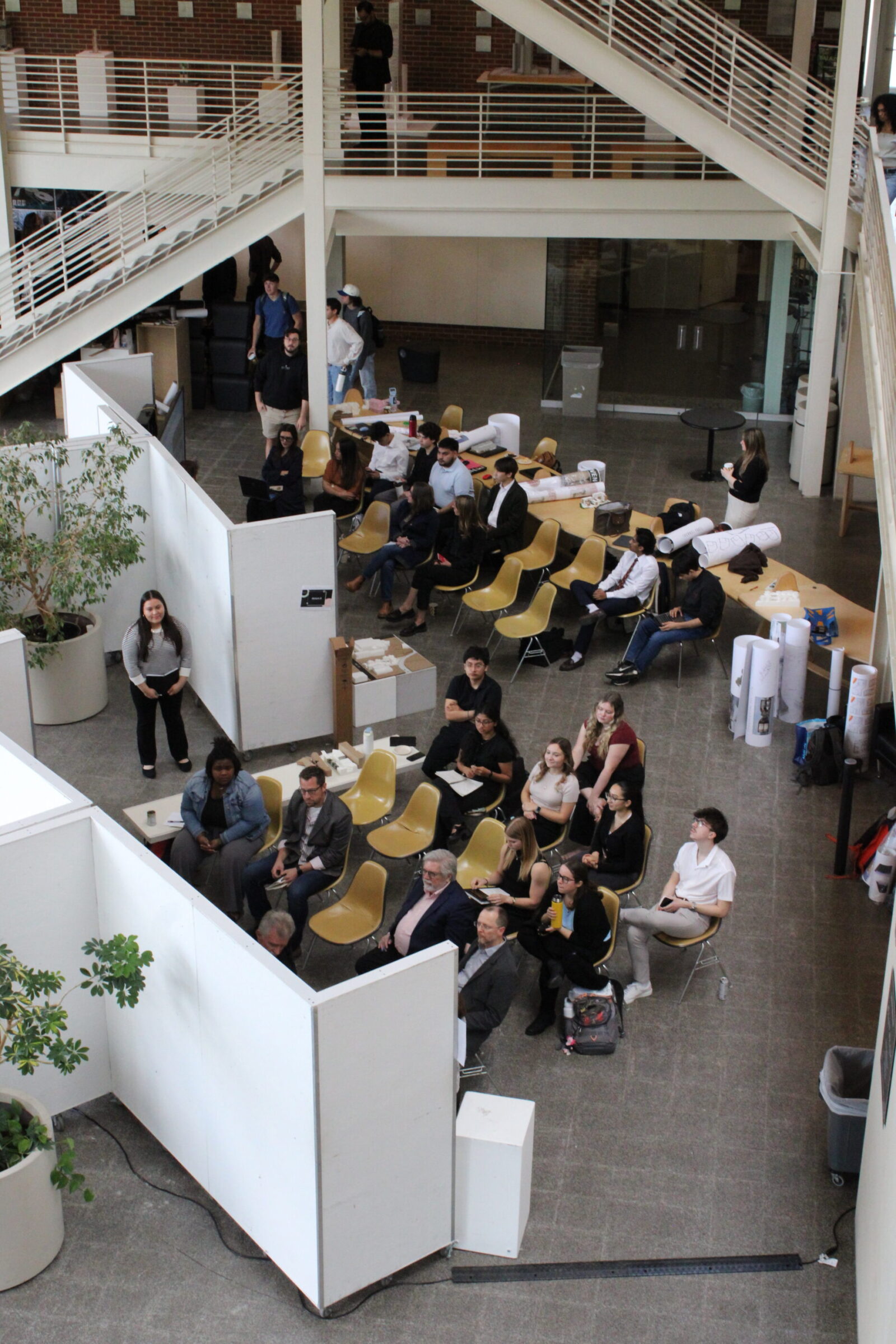 Professors and students sitting watching students present their work 