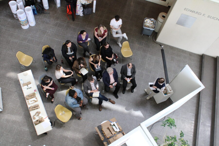 overhead shot of students and professors sitting watching a presentation