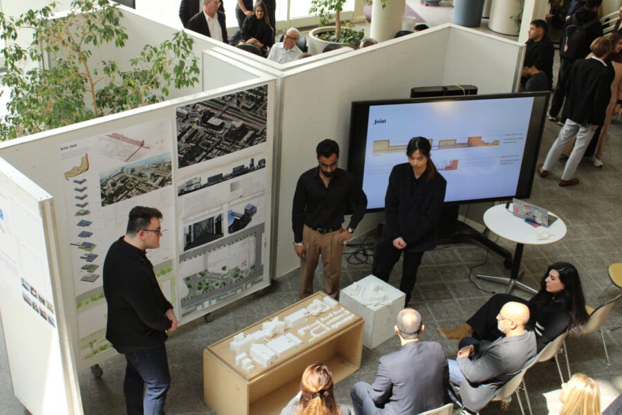 Three students presenting their architecture boards to reviewers