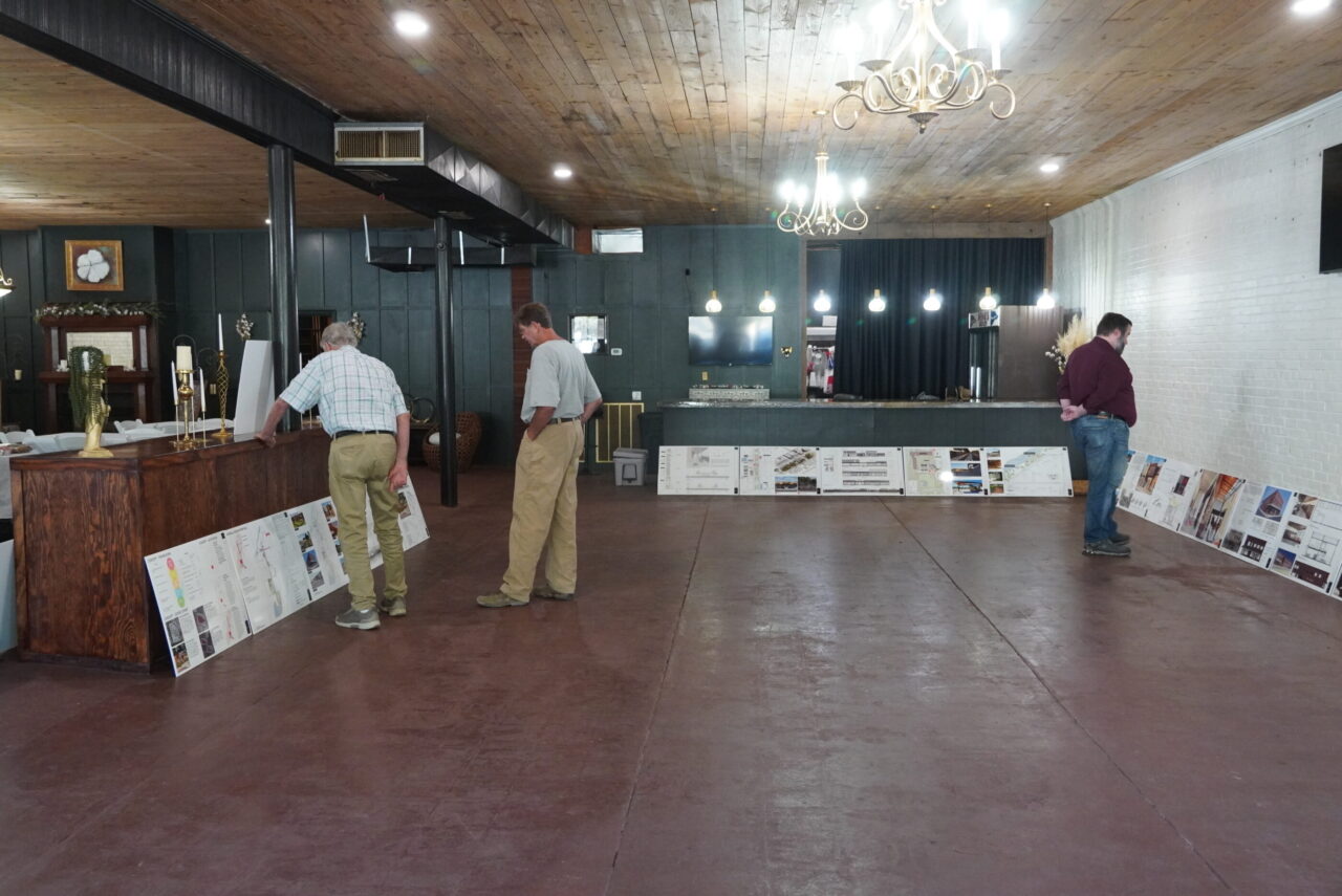 Local residents and city leaders looking at work placed around the room. 