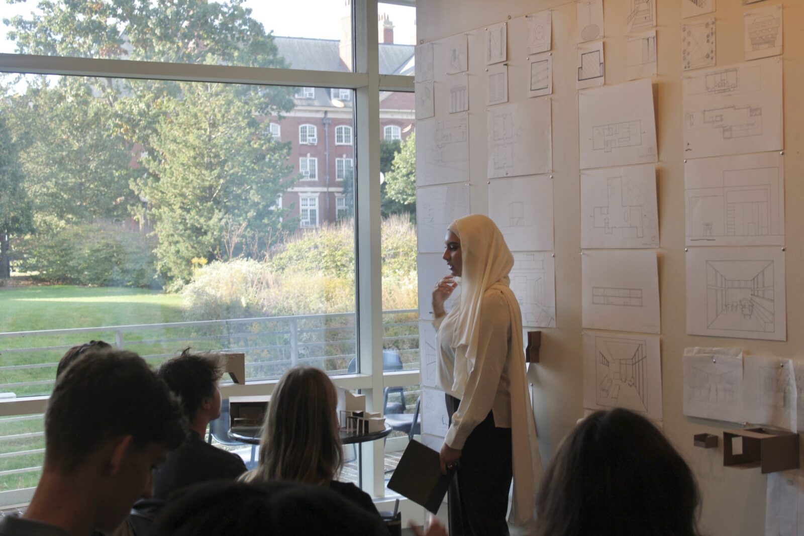student presenting work pinned up on wall