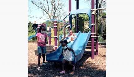 Children wearing masks near playground equipment