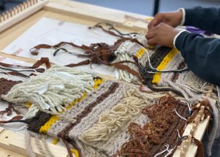 Weaving with loom and student's hands