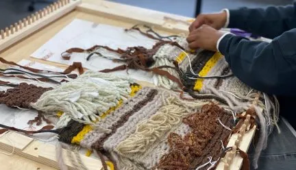 Weaving with loom and student's hands