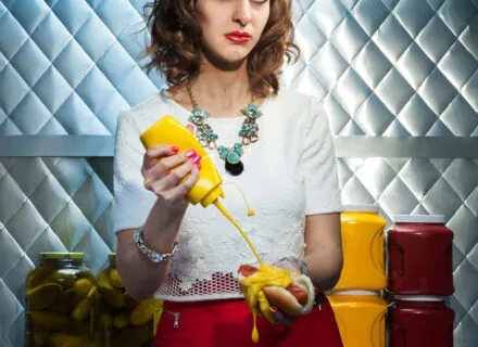 Photograph of a figure squirting mustard on a hot dog