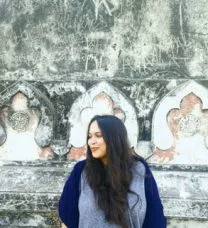 Portrait of the smiling student standing before a textured architectural surface