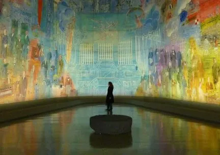 Photo of a museum visitor viewing an installation of a colorful curved mural