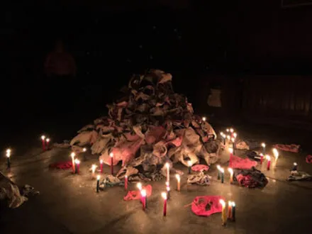 Photo of a pile of undergarments in a dark space lit by candles