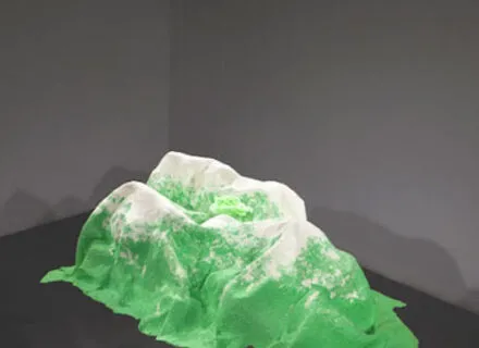Photo of abstract sculptural artwork that looks like green mountainous landforms with white peaks