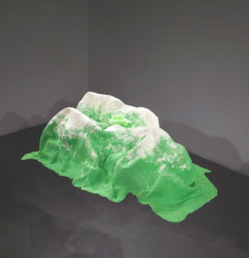 Photo of abstract sculptural artwork that looks like green mountainous landforms with white peaks