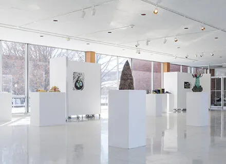 Photo of artworks on pedestals in a gallery with picture windows