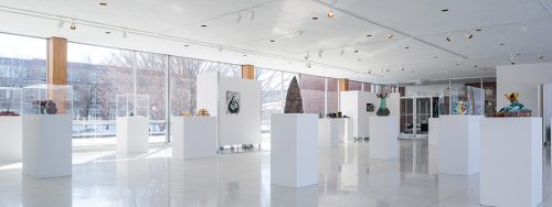 Photo of artworks on pedestals in a gallery with picture windows