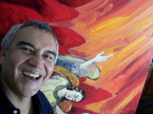 Portrait of Carlos Llerena Aguirre laughinig with a bright painting behind