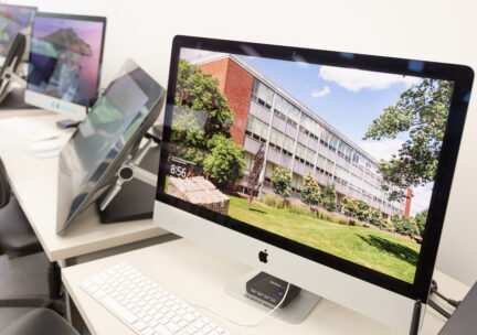 Photo of a row of imacs with the A&D building on the desktop