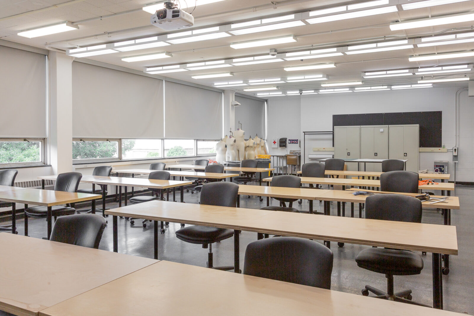 photograph of textile lab, wooden tables in rows with fashion equipment in the back