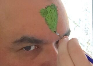 portrait of Jorge Lucero's forhead being painted a green triangle