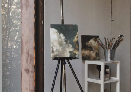 View of studio with painting of clouds on an easel