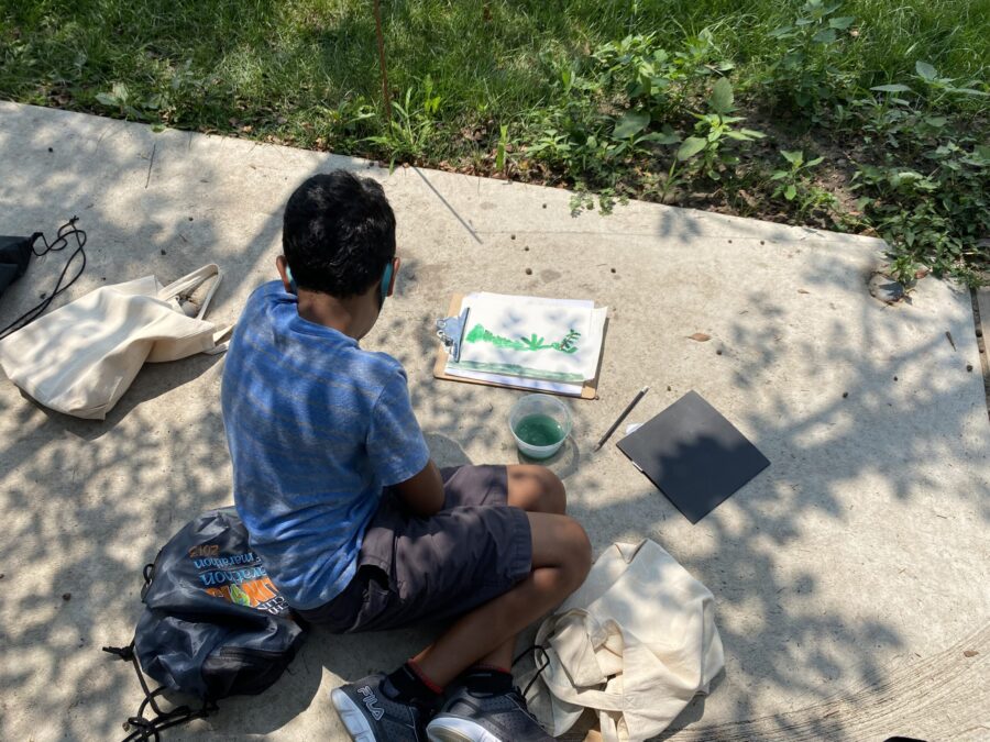 Child painting from nature with a shadow of a tree cast over them