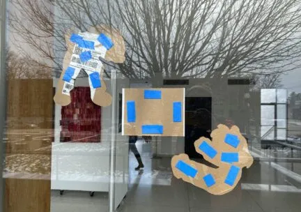 three artworks installed on a window seen from behind, the hanging apparatus is prominent