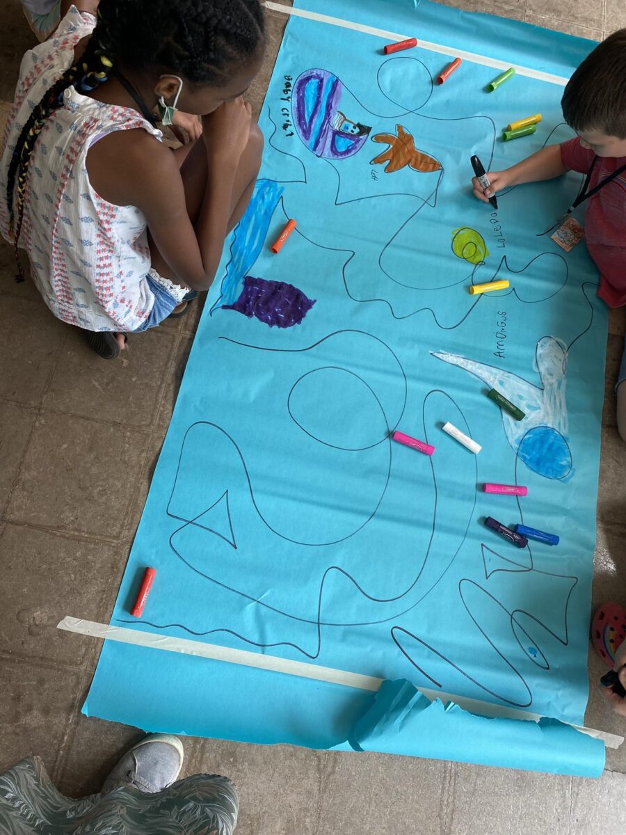 two children draw together on a large piece of paper