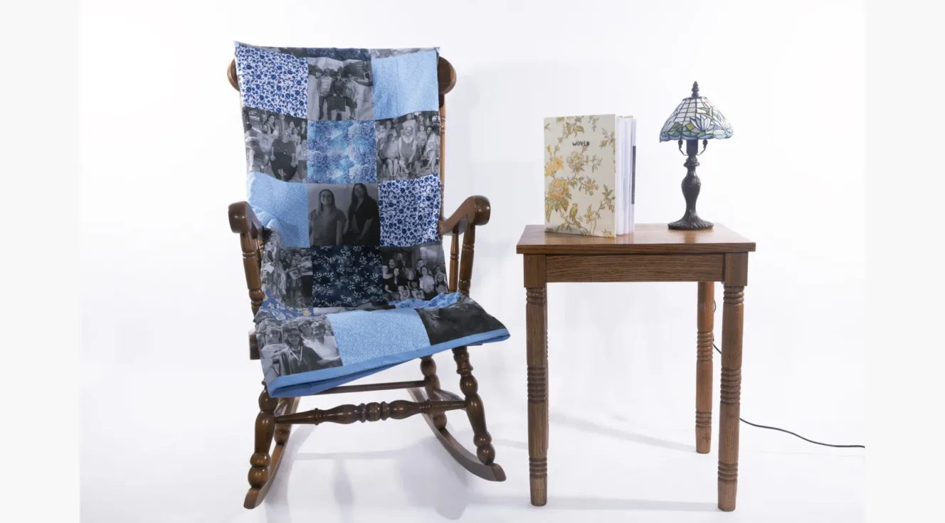 Installation with quilt, rocking chair, photo book, and table