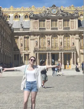 woman standing with arms stretch out in front of a building