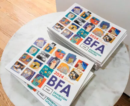 stacks of BFA catalogs on a table in a gallery setting