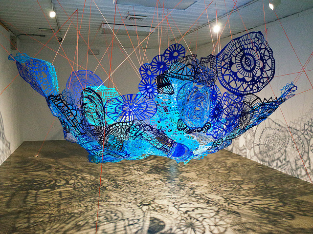3d artwork hanging from the ceiling in an empty, bright art gallery