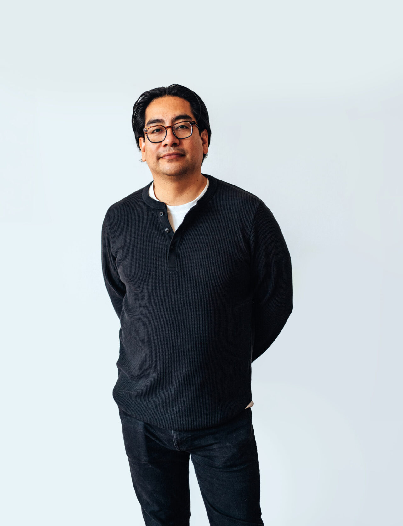 portrait of someone wearing black, standing casually with hands behind their back