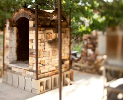 photo of a kiln outside with leaves surrounding it