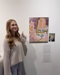 person stands and points to artwork on wall