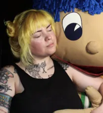 young woman next to a doll
