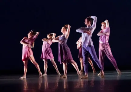 6 dancers in a pose with arm over their heads and the other around their chests