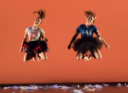Two woman jump high up into the air