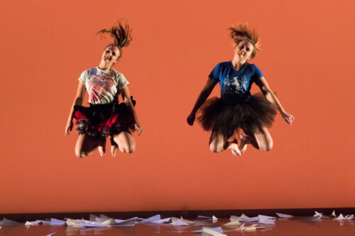 Two woman jump high up into the air