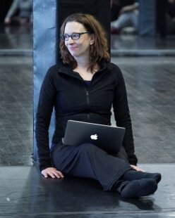Sara sits on the floor with her laptop computer open