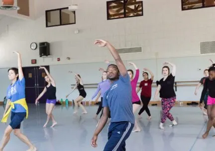 A group of dancers reach their left arm up