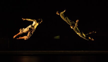 Three dancers flying through the air on stage